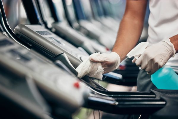 Cleaning, treadmill and sanitizing equipment in gym for bacteria, germs or protection from covid. D.