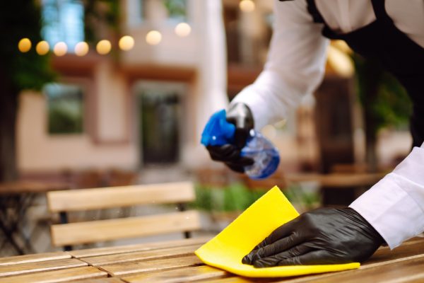 Disinfecting to prevent COVID-19. Waiter cleaning the table with Disinfectant Spray in a restaurant.